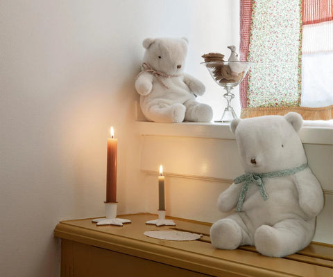 Off-white teddy bear plush with a green ribbon bow, seated beside a smaller bear