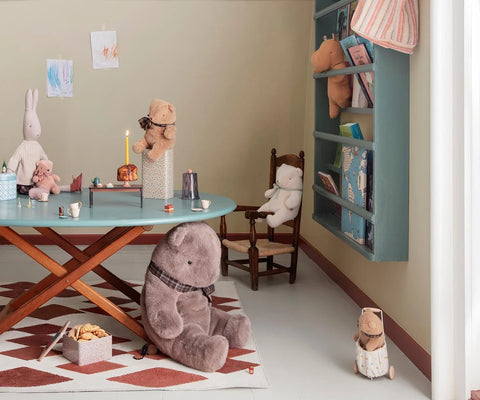 Mini teddy bear plush displayed in a playroom beside other stuffed animals