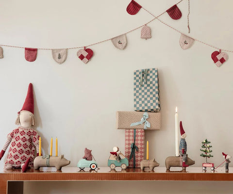 Christmas mouse toy in a red hat and patterned sweater, displayed among holiday decorations