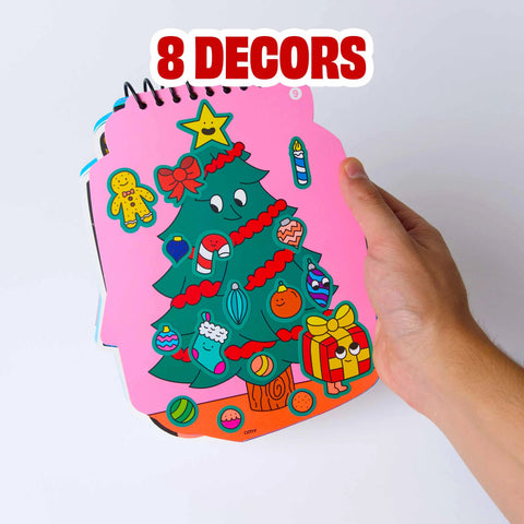 Christmas sticker activity notebook page with tree scene and 8 decors prompt, hand applying sticker