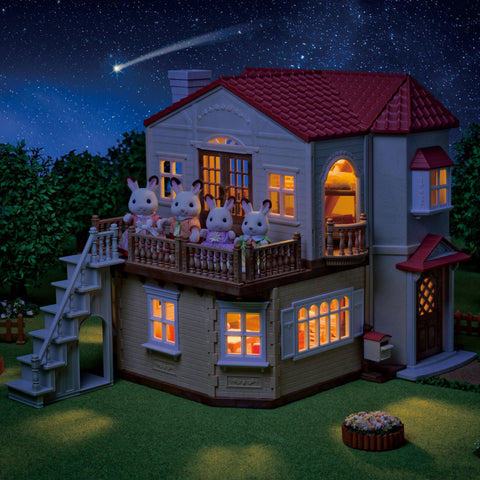 Illuminated wooden dollhouse with red roof, glowing windows and bunny porch figures