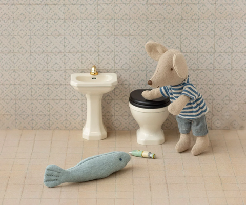 Miniature off-white pedestal sink with a gold faucet, shown beside a toy toilet
