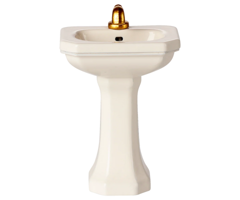 Front view of an off-white miniature pedestal sink with a gold faucet