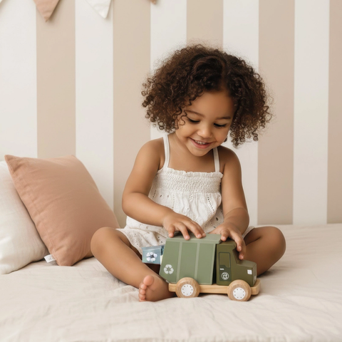 Kids playing with green toy garbage truck with open cabin and wheels on floor